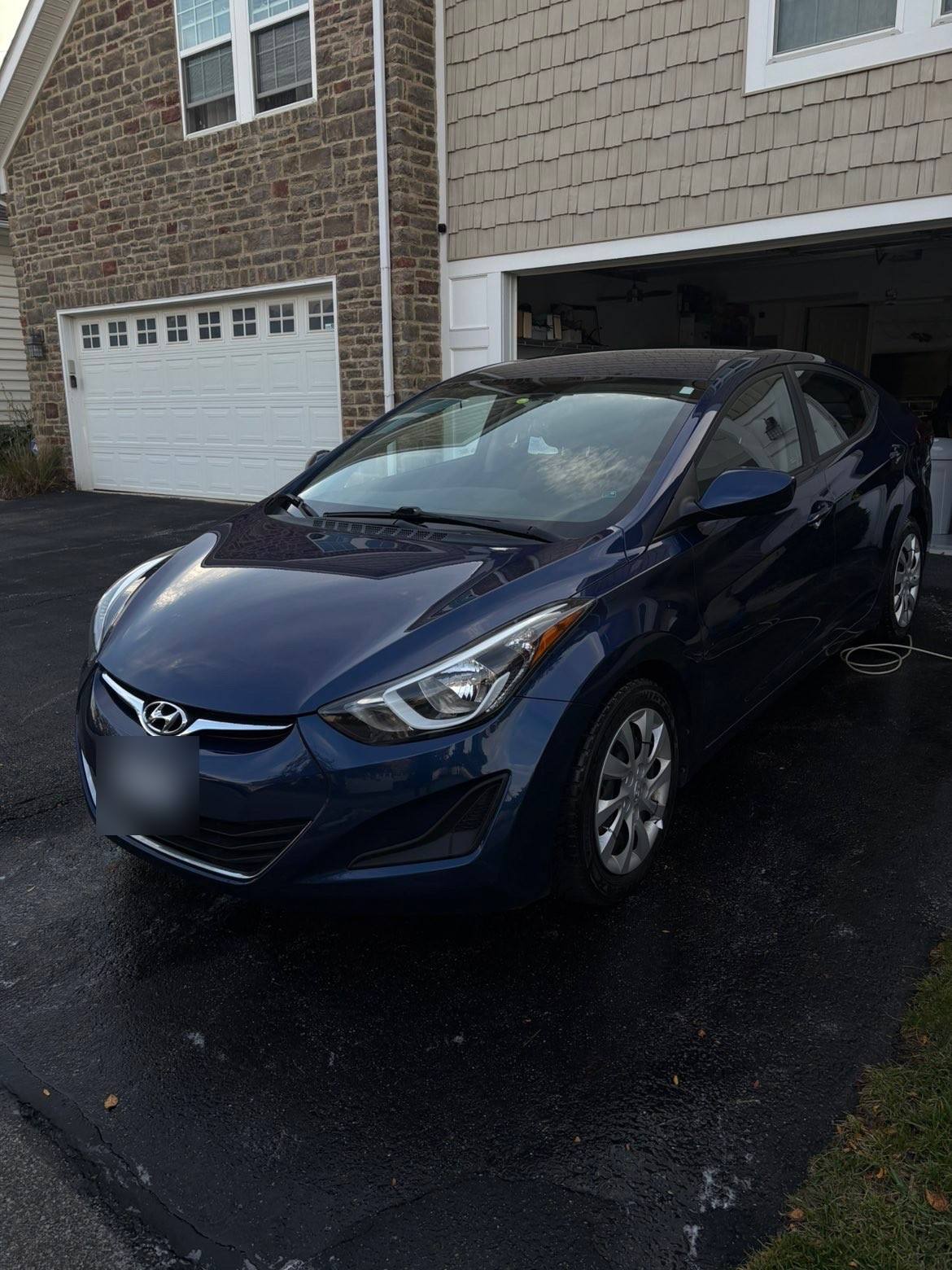 Blue Hyundai Elantra on a wet driveway after an exterior detail