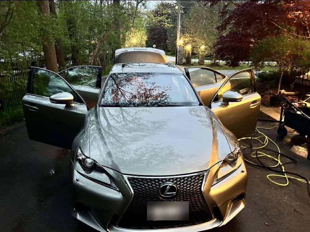 The same Lexus from the front after the detail, doors open on a wet driveway