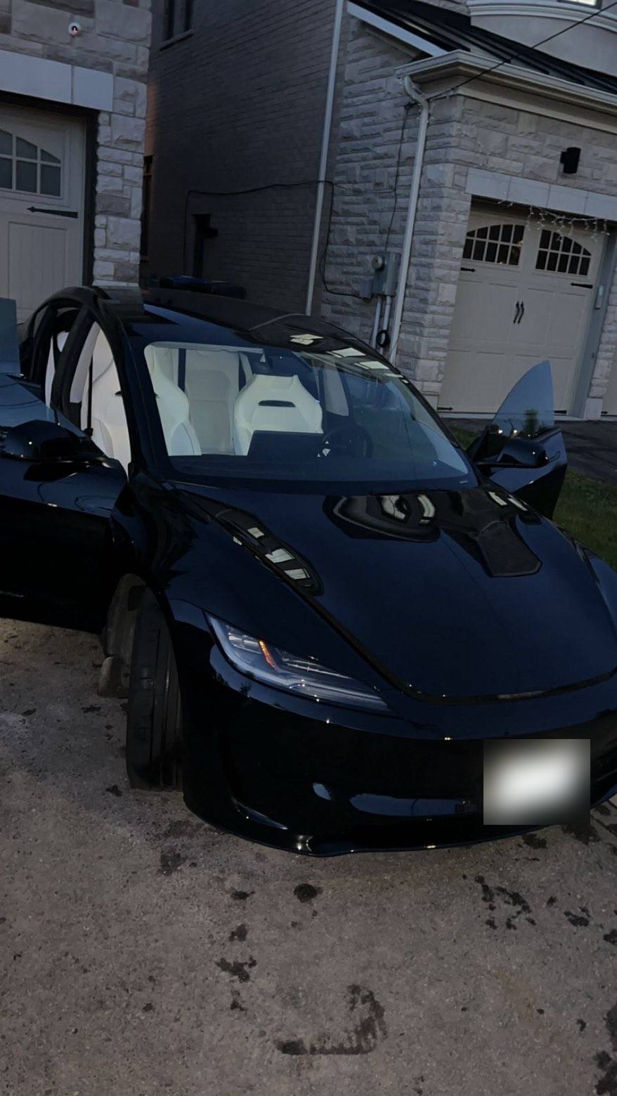 Black Tesla Model 3 from the front after a full detail, doors open