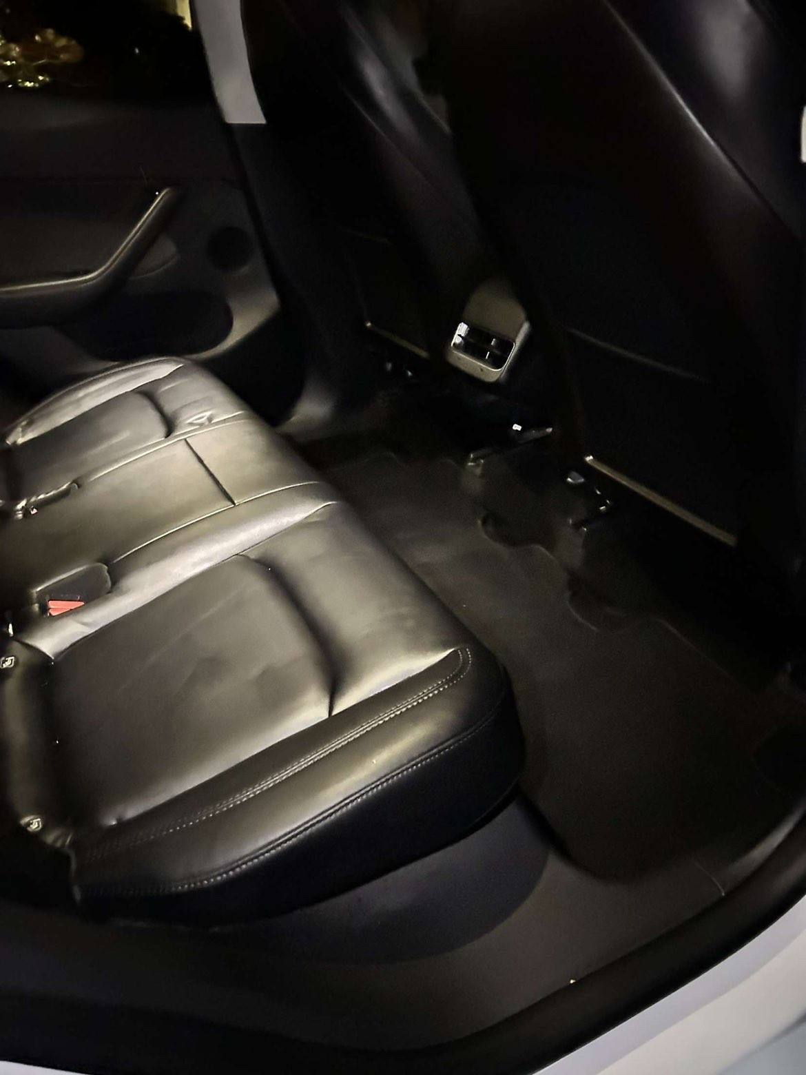 Black leather rear seat and floor of the same Tesla after the detail